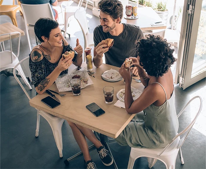 amigos comiendo y pagando con su tarjeta vexi american express